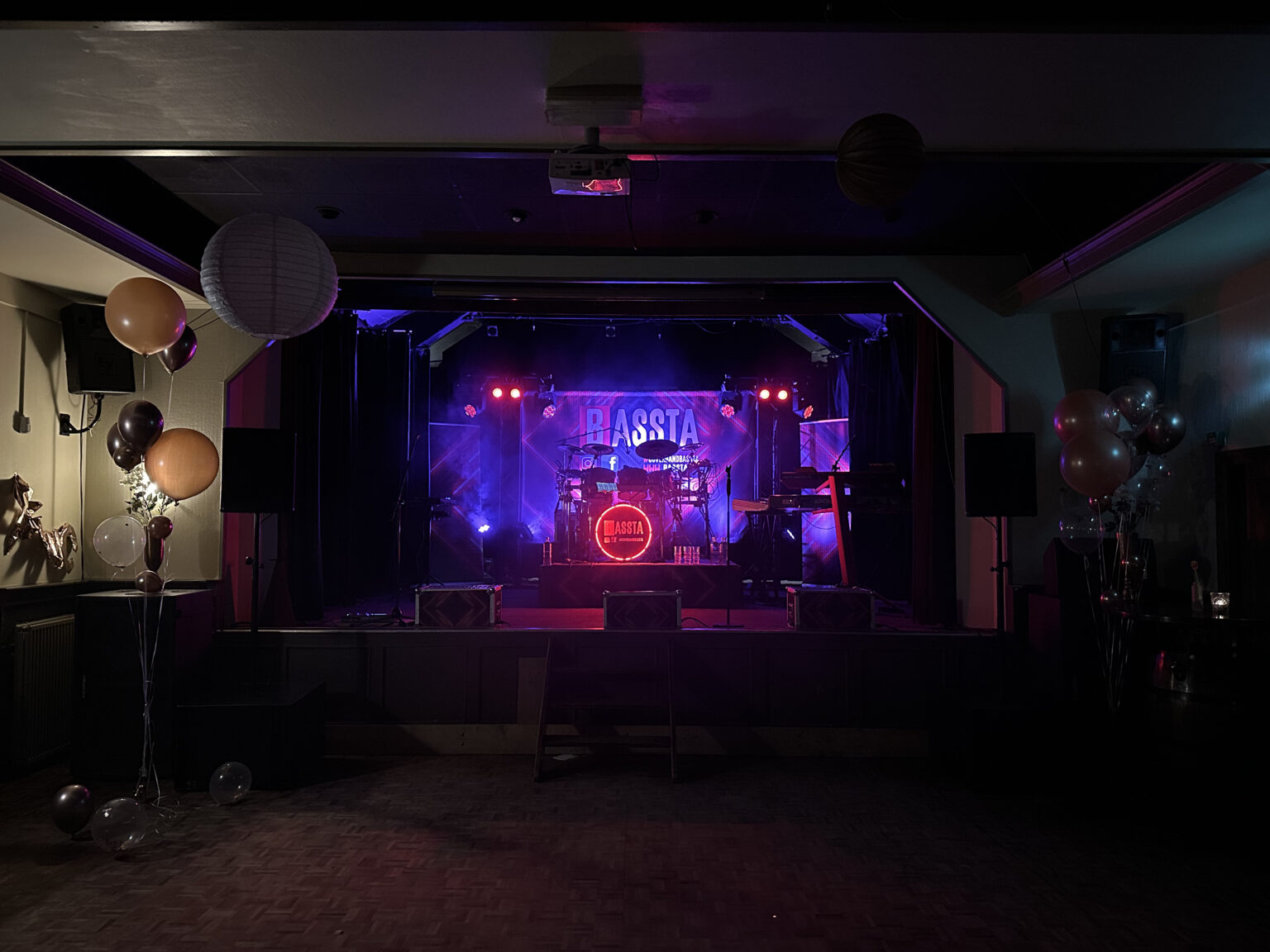 Podium met paars licht, speakers en drumstel